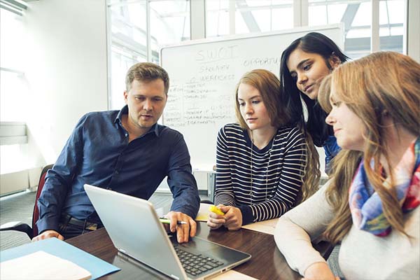 A group of people around a laptop in a boardroom