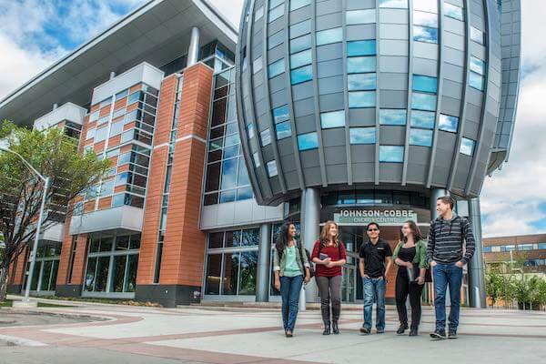 A group of students standing outside the entrance to the Johnson-Cobbe Energy Centre on SAIT campus.