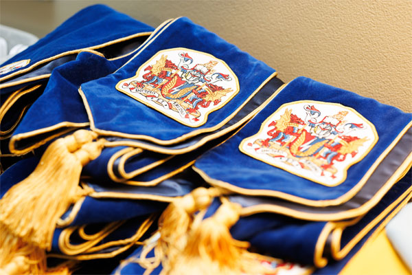 A close up of convocation stoles with the SAIT coat of arms on them.