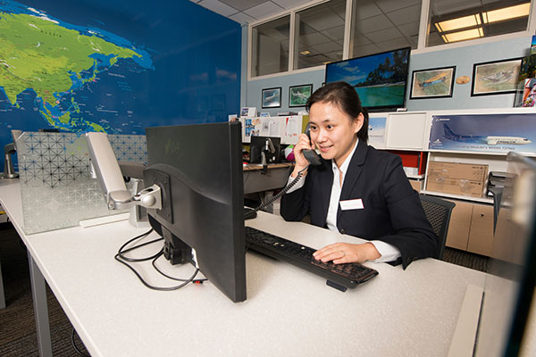 A Travel and Tourism student speaks with a client on the phone in SAIT's travel centre Destinations.