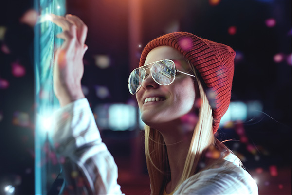 A girl interacting with a touch screen in a dark room with neon lights.