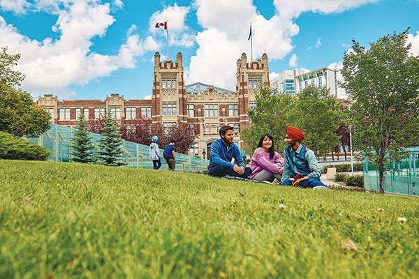 students sitting on the grass infront of building