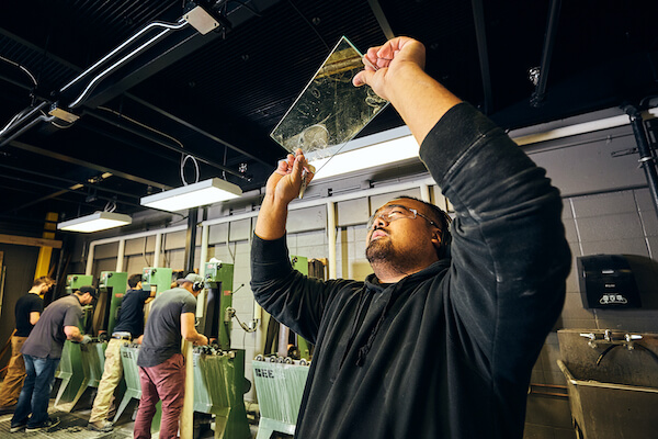 Man holding up a small pane of glass and looking through it