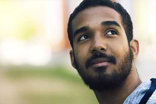 A man standing outside on SAIT campus looks up toward something off-camera.