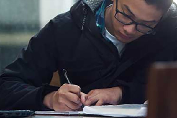 A SAIT student writes notes while studying.