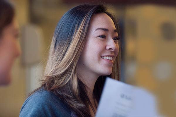 The profile of a SAIT student smiling. She has straight, shoulder-length hair.