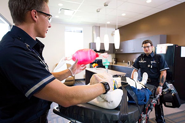 Two EMS students work together to intubate a manikin.