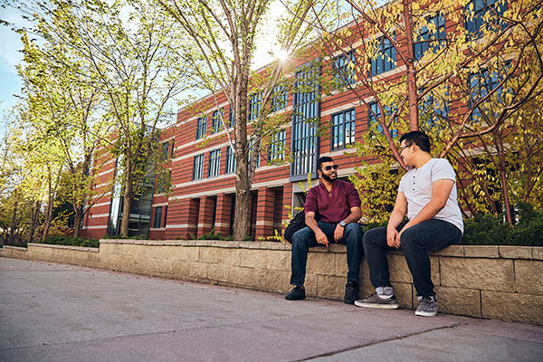 two men chat infront of building