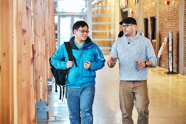Two men talking to each other and walking towards the camers