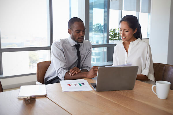 Two people sitting at a table looking at a laptop