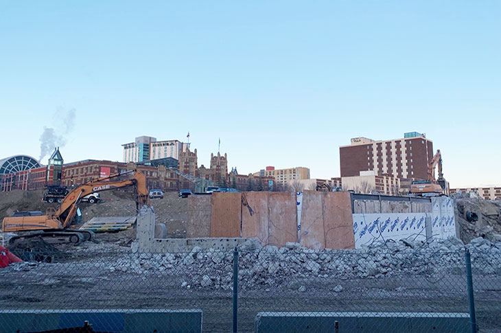 View of Campus Centre construction site from the CTrain platform. Heavy machinery pulling down building components.