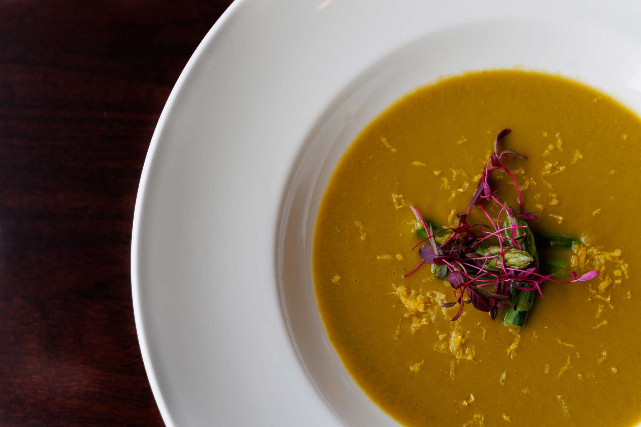 close up of leek veloute with micro greens and edible flowers garnish