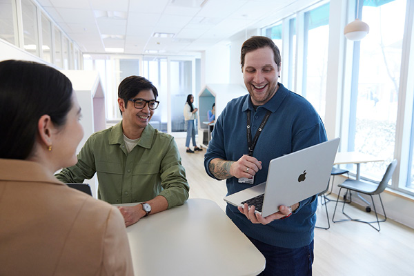 A man showing two other people something on his laptop