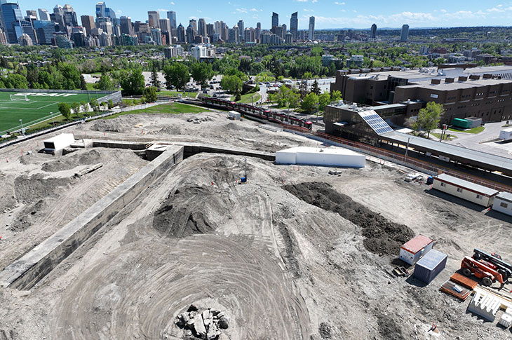 aerial view of the taylor family campus centre construction site, with a view of downtown calgary in the background