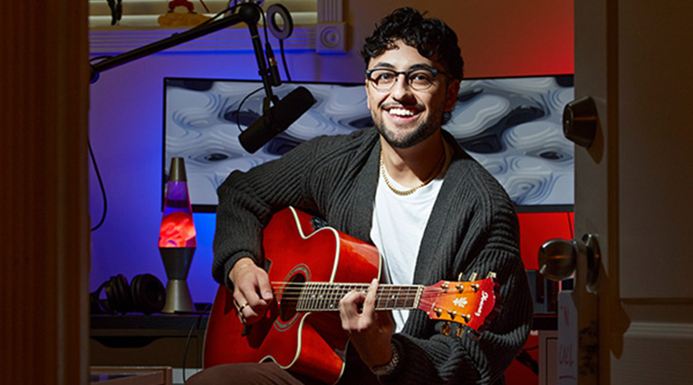Young man siting with red guitar in personal home studio
