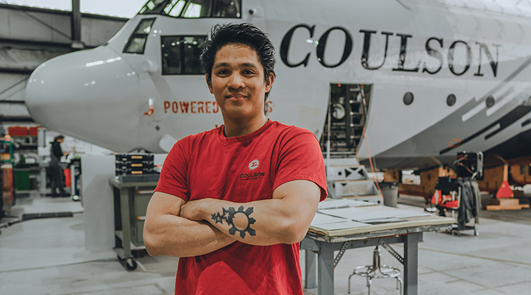 Filipino man standing in front of a plane in hangar