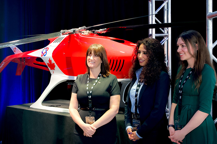 Three SAIT community members standing in front of a drone