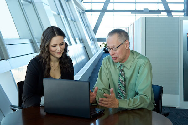 Two people discussing with a laptop in front of them