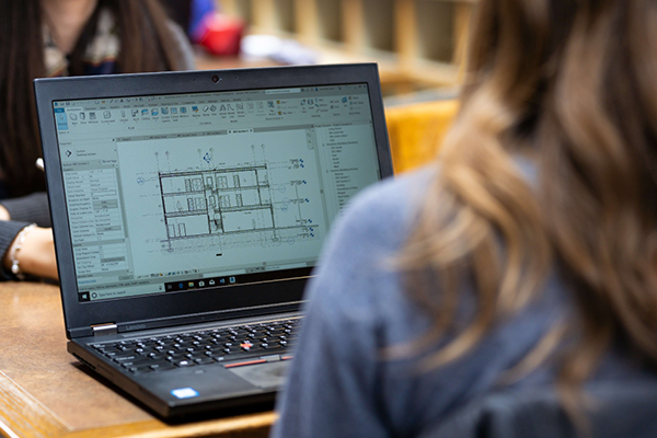 The screen of a laptop, seen over the shoulder of a student.