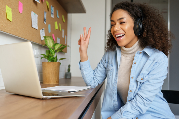 A young woman at a laptop giving a peace sign